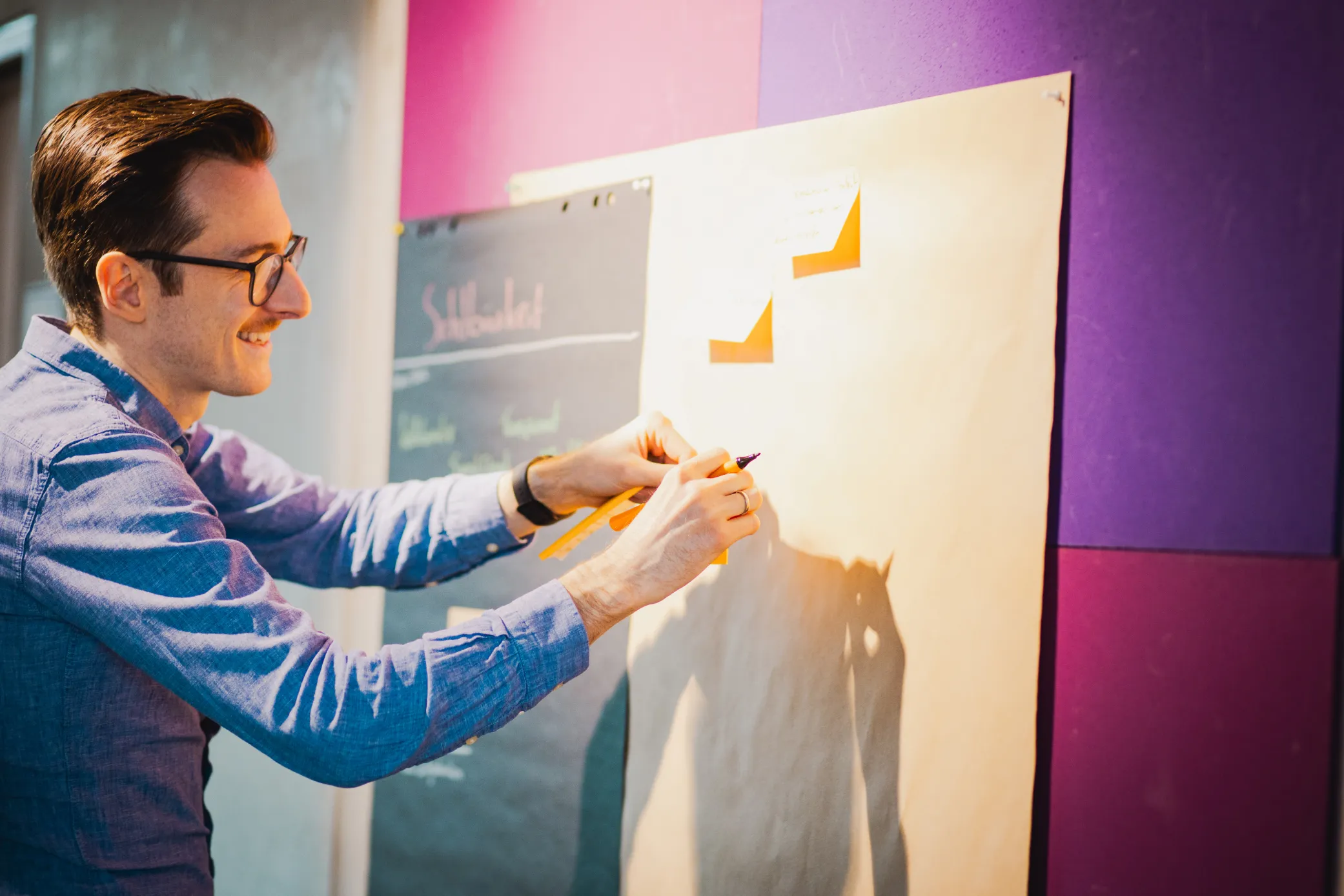 UX-Research-Workshop bei mindmatters: Kollege beschriftet Haftnotizen an einer Metaplanwand zur digitalen Bedarfsanalyse